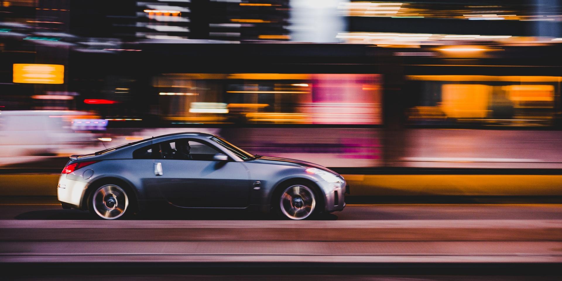 Panning photo of grey coupe on road